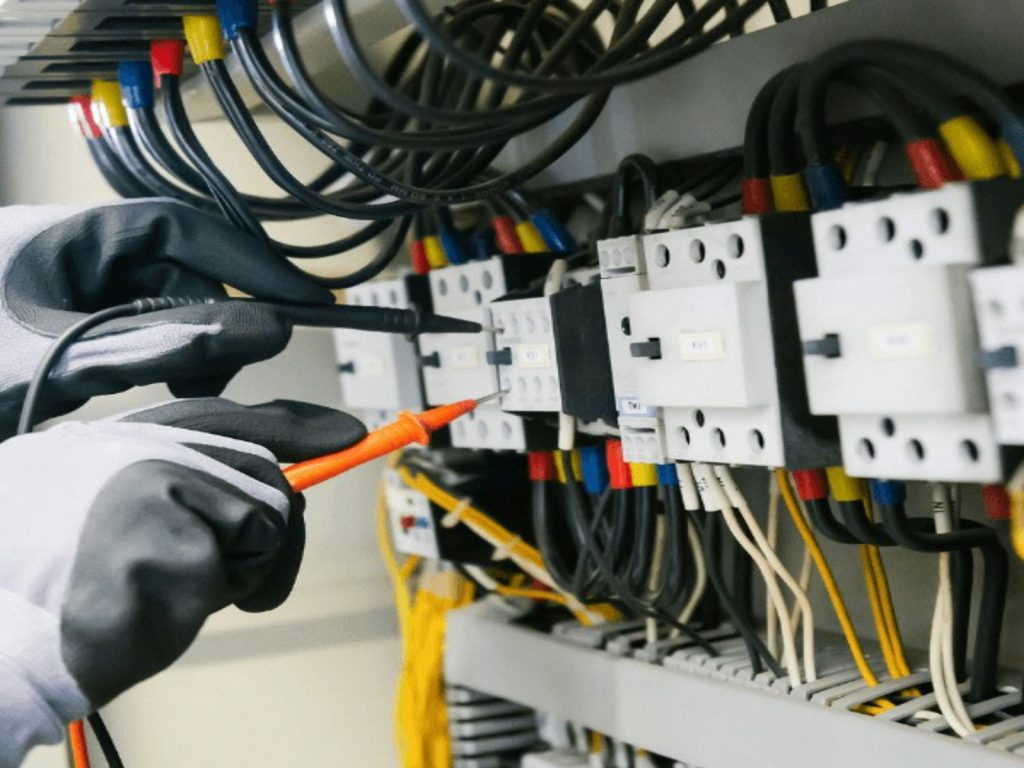 Electrician inspecting a breaker panel with a multimeter