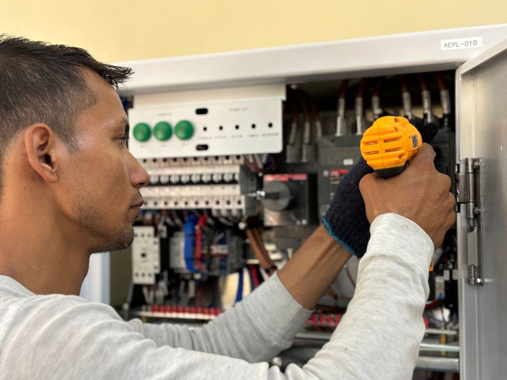 Electrician servicing switchgear inside a cabinet