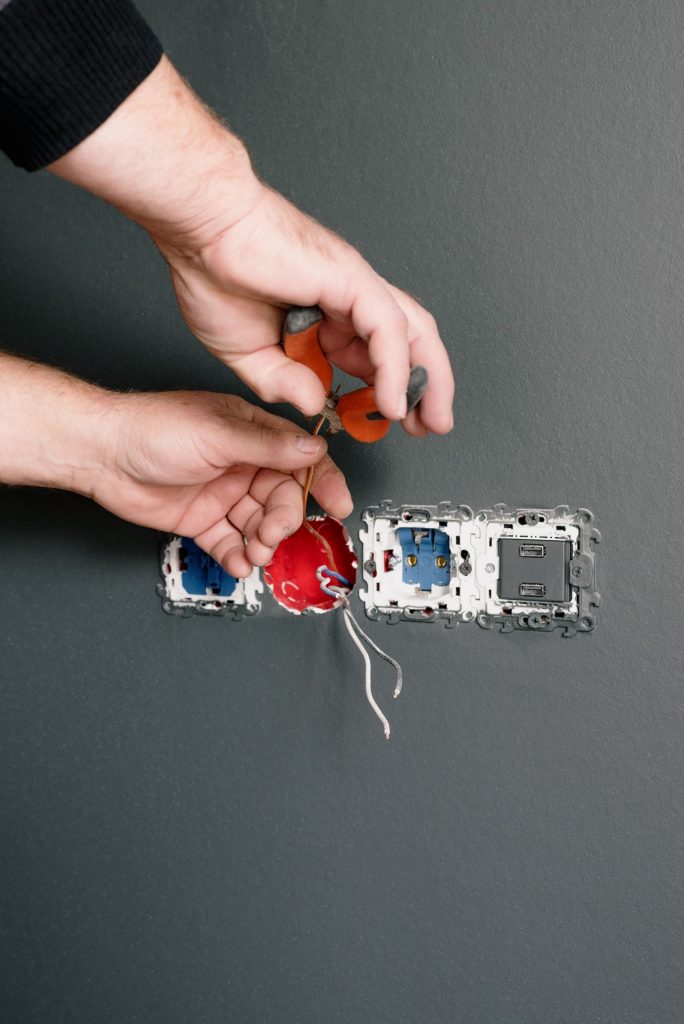 Electrician connecting wires to a socket outlet during repair